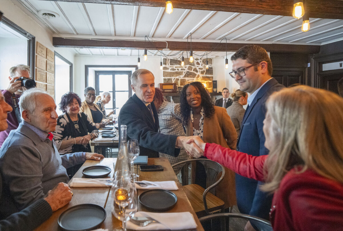 Prime Minister Mark Carney, centre, and local candidate Tatiana Auguste, centre right, visit a local pub in her riding of Terrebonne, Que., on Feb. 17, 2026. (Christinne Muschi/The Canadian Press)