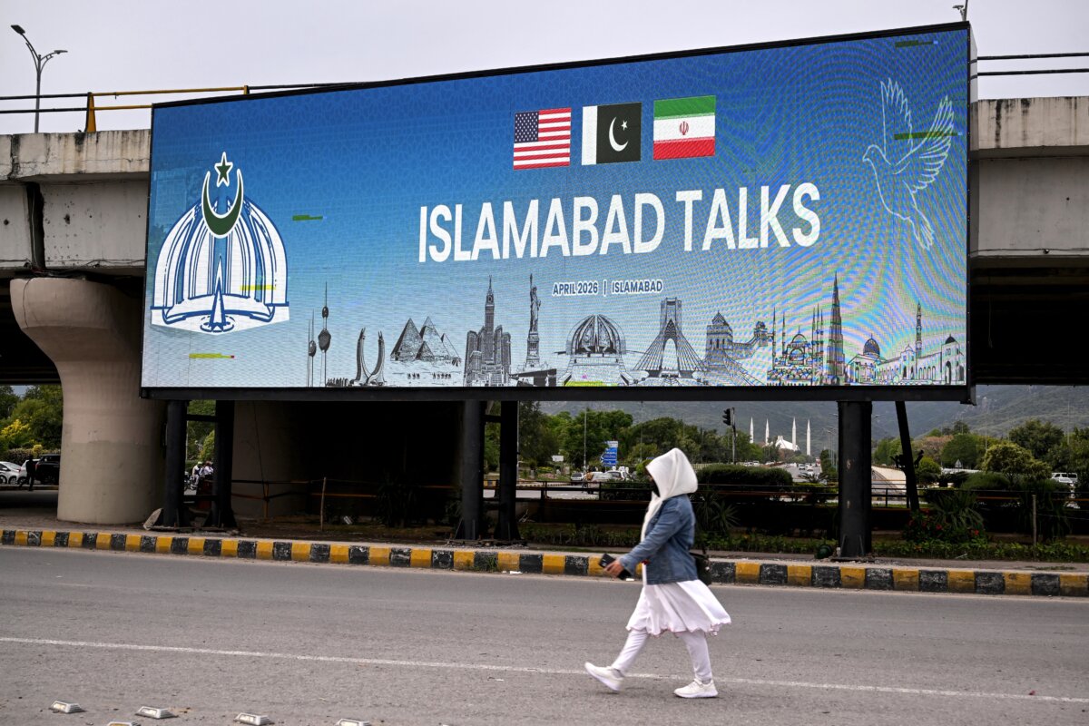 A woman walks past a digital screen displaying news of U.S.–Iran peace talks along a road in Islamabad, Pakistan, on April 10, 2026. (Farooq Naeem/AFP via Getty Images)