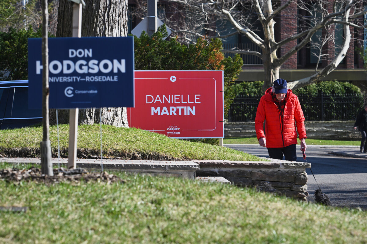 Pedestrians pass campaign signage ahead of a byelection in the riding of University-Rosedale, in Toronto, on April 9, 2026. (The Canadian Press/Sammy Kogan)
