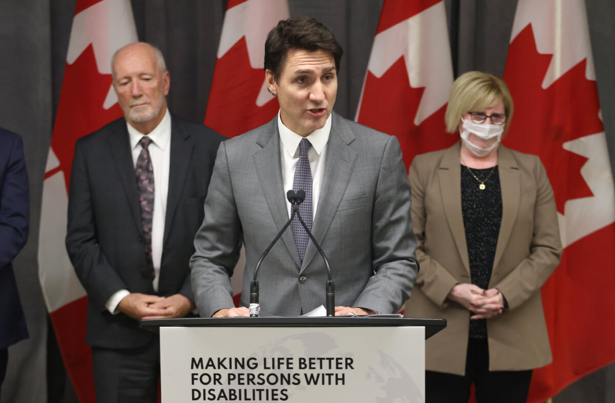 Senator Brent Cotter (L) and Employment, Workforce Development and Disability Inclusion Minister Carla Qualtrough look on as Prime Minister Justin Trudeau speaks at a press conference in Ottawa on Nov. 29, 2022. (The Canadian Press/Patrick Doyle)