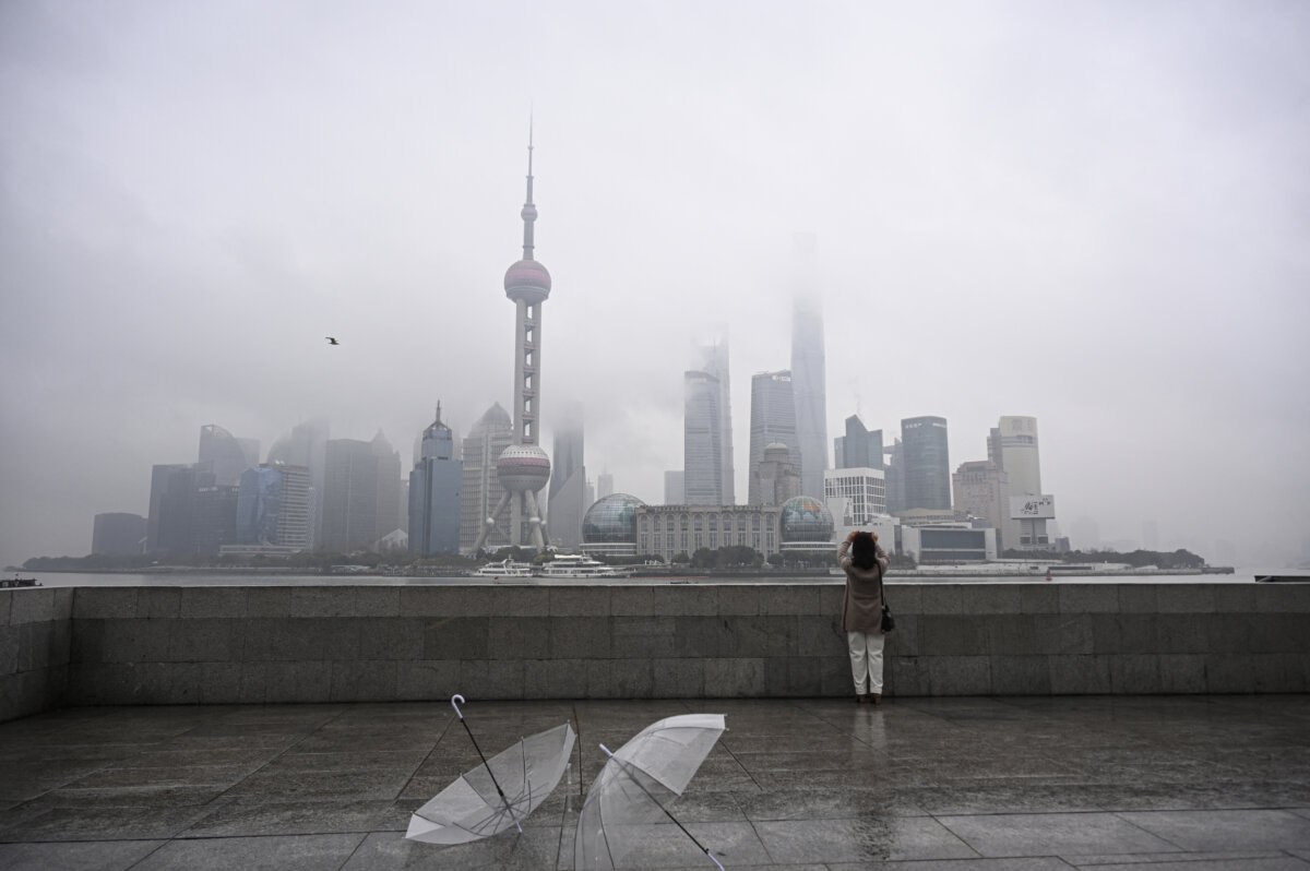 A woman takes a photo of the Lujiazui financial district from across the Huangpu River on the Bund promenade, in Shanghai on March 5, 2026. (Jade Gao/AFP via Getty Images)