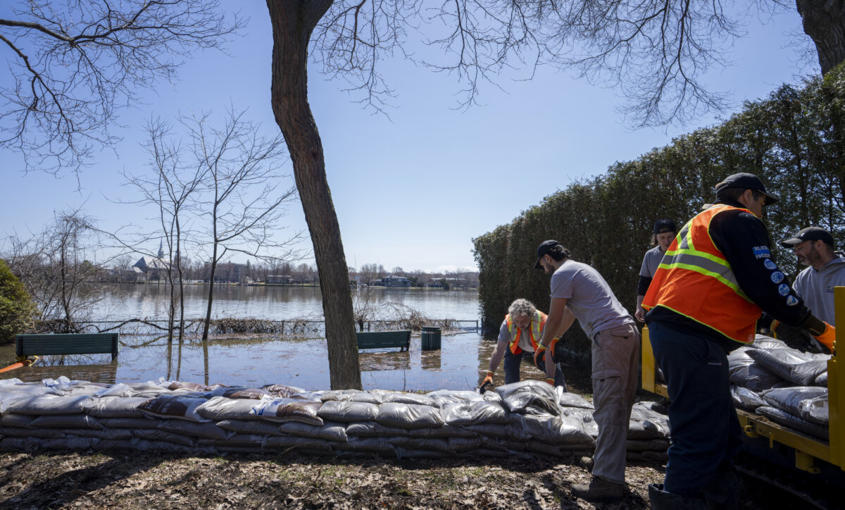 City workers construct a dike using sandbags near a flooded park as they prepare for flooding in Ile-Bizard, Que., on April 17, 2026. (The Canadian Press/Christinne Muschi)