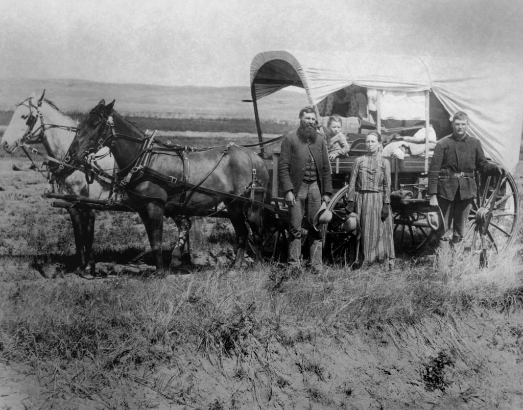 A family of pioneer settlers pose next to their covered wagon, 1886. (Photo by FPG/Getty Images)