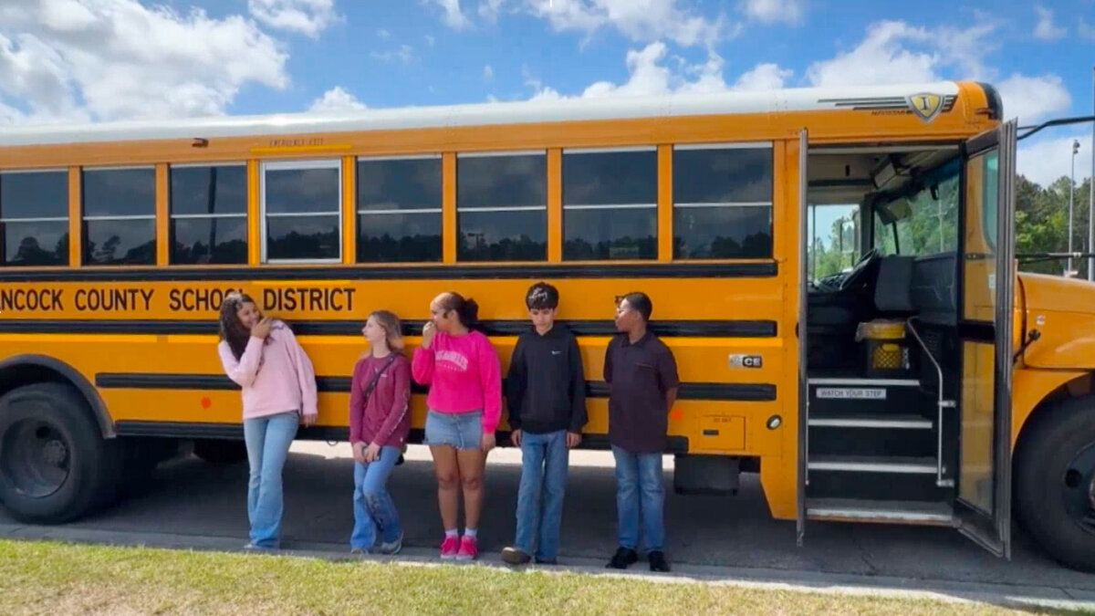 Five middle school students, who helped stop a bus after their driver passed out during a medical emergency, stand outside a bus in Hancock County, Miss., on April 23, 2026. (WLOX via AP)