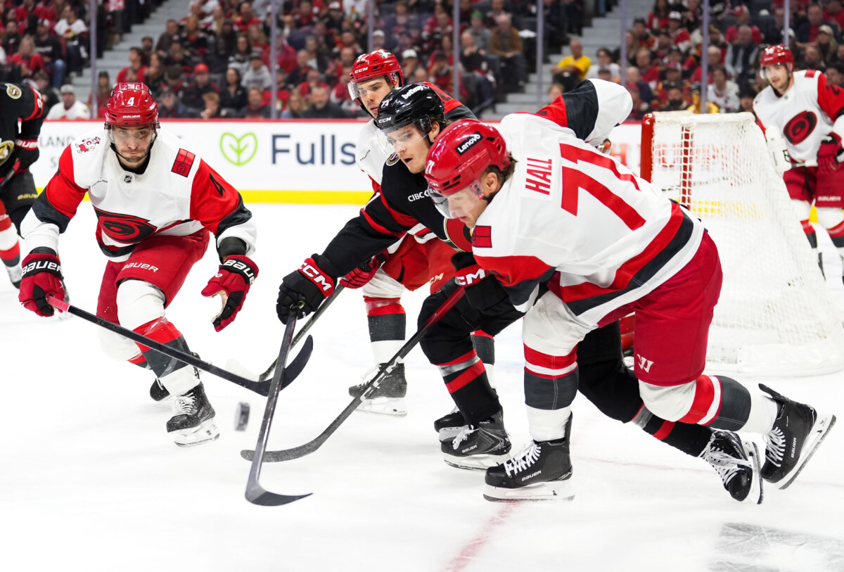 Ridly Greig #71 of the Ottawa Senators battles for puck possession against Shayne Gostisbehere #4, Logan Stankoven #22 and Taylor Hall #71 of the Carolina Hurricanes during the second period in Game Three of the First Round of the 2026 Stanley Cup Playoffs at Canadian Tire Centre in Ottawa on April 23, 2026. (Tim Austen/Freestyle Photo/Getty Images)