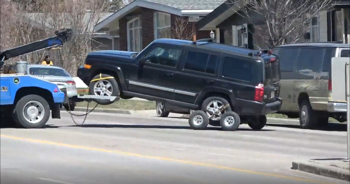 A vehicle where two children were found dead is being towed away as police watch the scene in Calgary on April 30, 2026. (The Canadian Press/Dayne Patterson)