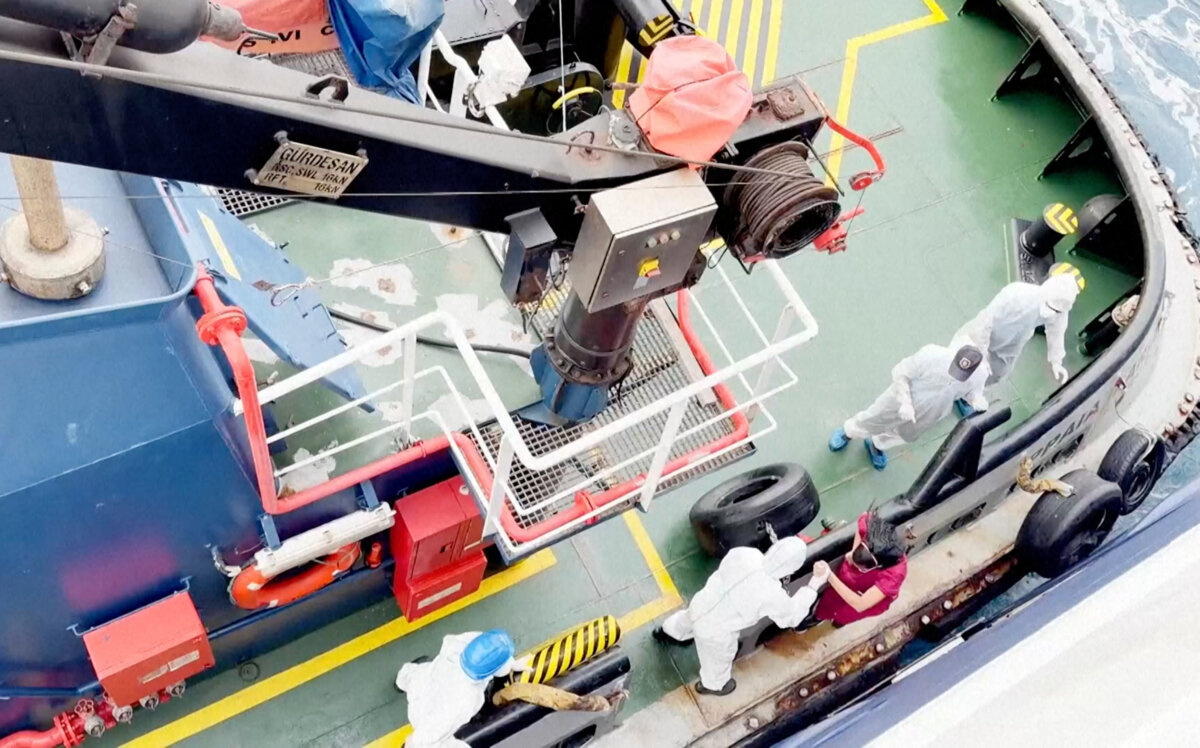 Health workers get off the Dutch-flagged MV Hondius, a cruise ship carrying nearly 150 people as it remains off Cape Verde after three passengers died and several others fell seriously ill in a suspected hantavirus outbreak, on May 4, 2026. (Qasem Elhato via AP)