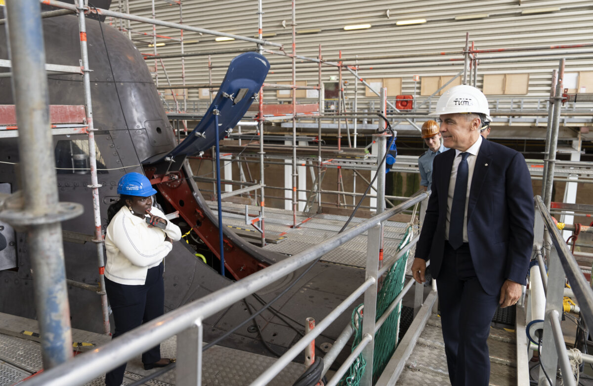 File photo -- Prime Minister Mark Carney looks over a 212A class submarine under maintenance as he tours Thyssenkrupp Marine Systems (TKMS), a submarine building facility in Kiel, Germany on Aug. 26, 2025. (The Canadian Press/Christinne Muschi)