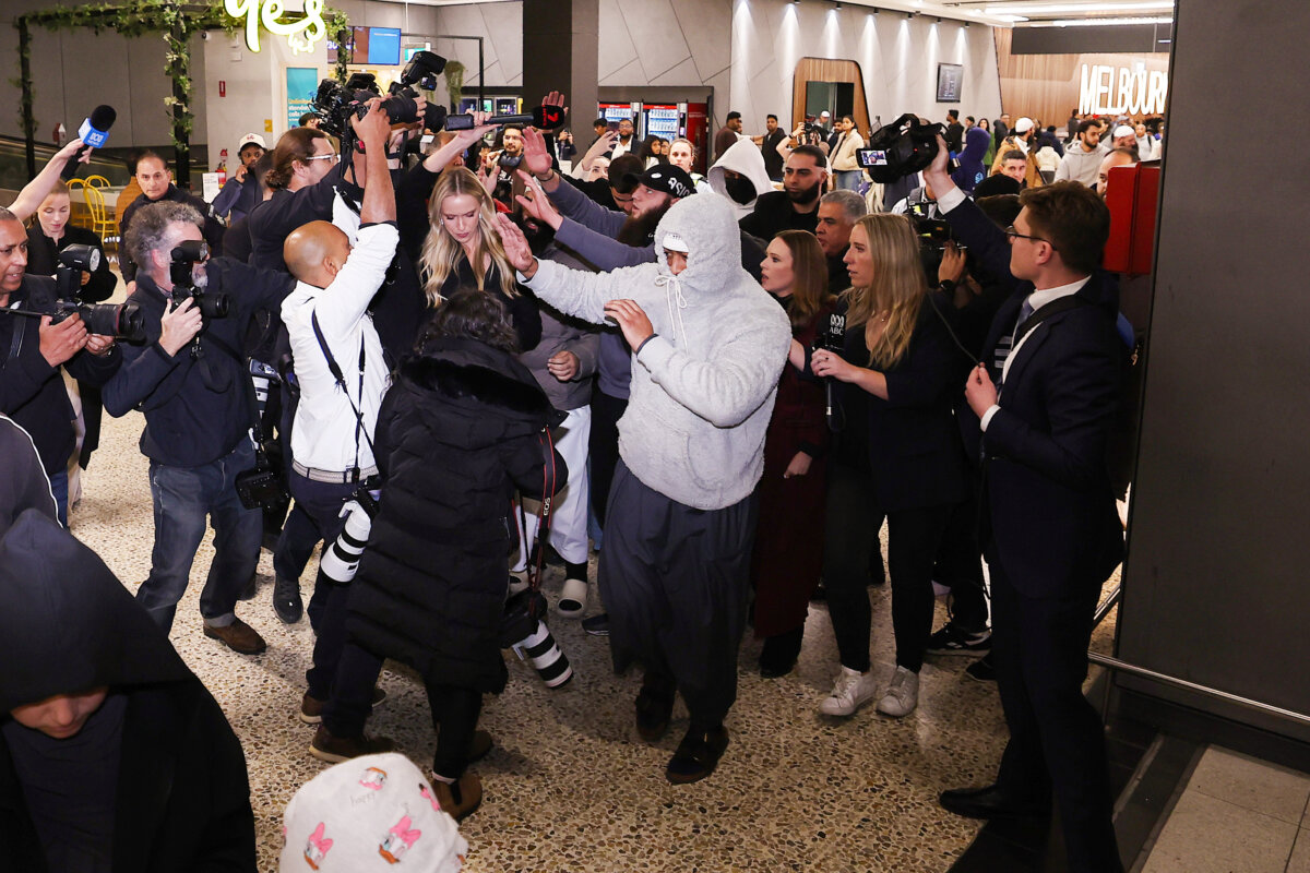 A group of supporters shield recently arrived people with links to ISIS as they arrive at Melbourne Airport in Melbourne, Australia, on May 7, 2026. (Morgan Hancock/Getty Images)