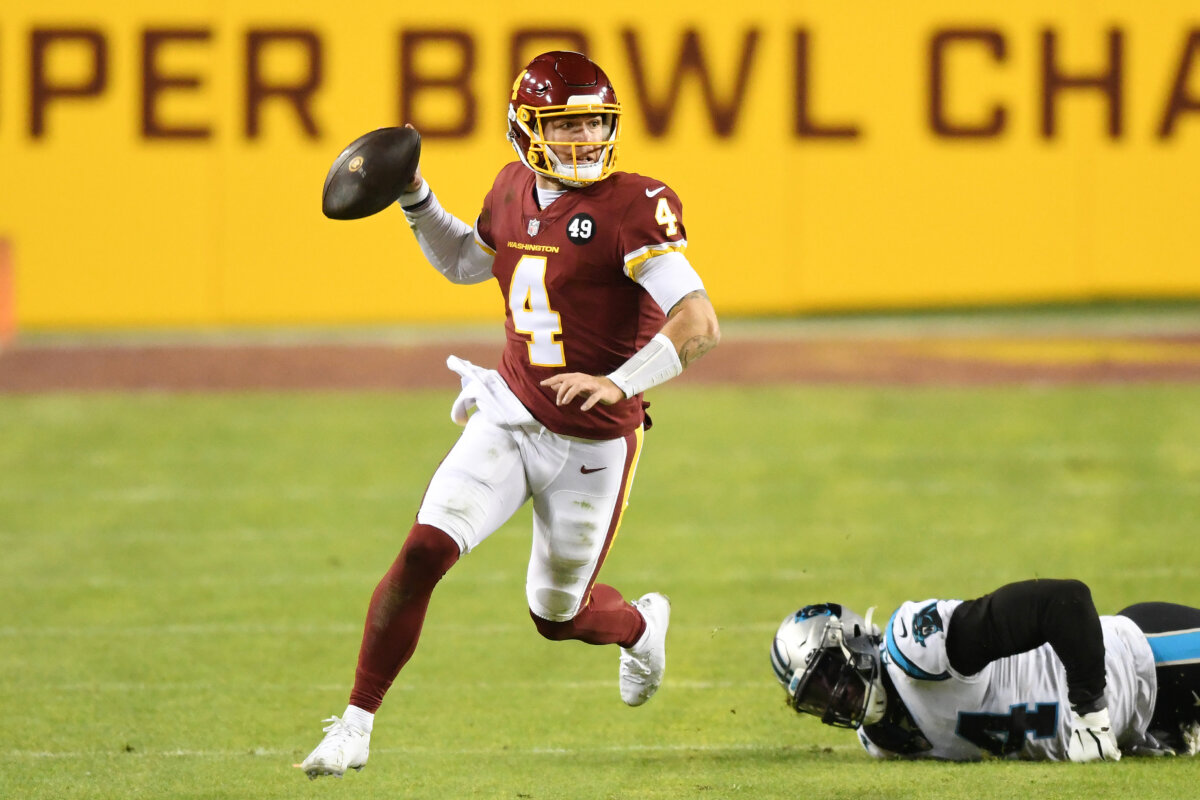 Taylor Heinicke #4 of the Washington Football Team scrambles with the ball away from the tackle of Efe Obada #94 of the Carolina Panthers during the third quarter at FedExField in Landover, Maryland, on Dec. 27, 2020. (Photo by Mitchell Layton/Getty Images)