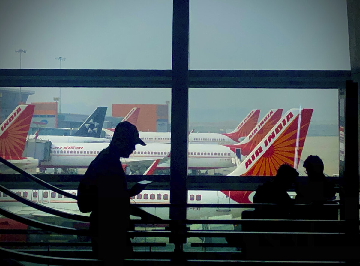 A man is silhouetted against an airport window with Air India aircraft parked in the background in New Delhi, India, on Oct. 31, 2023. (AP Photo/Manish Swarup, File)