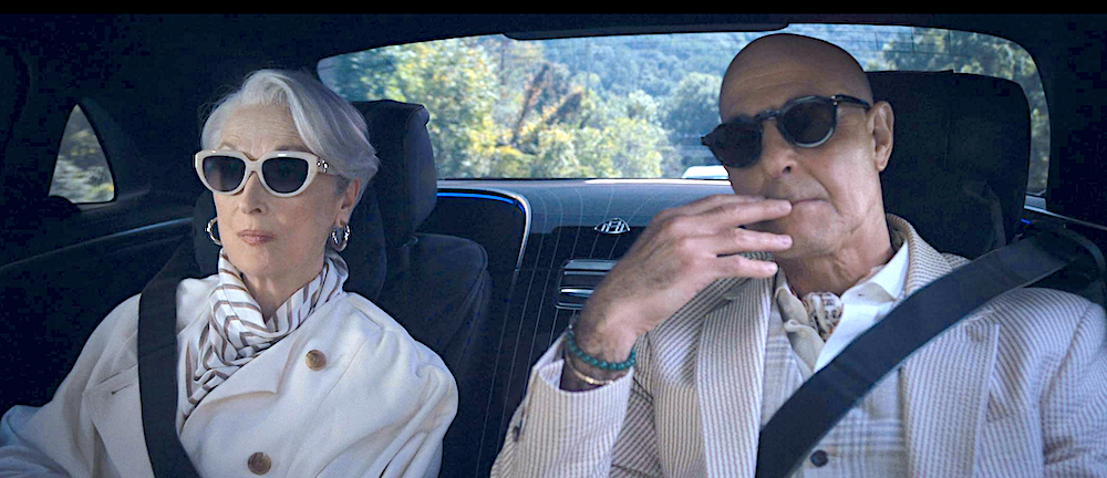 man and woman, wearing white outfits, sit in the back of a car in The Devil Wear Prada 2