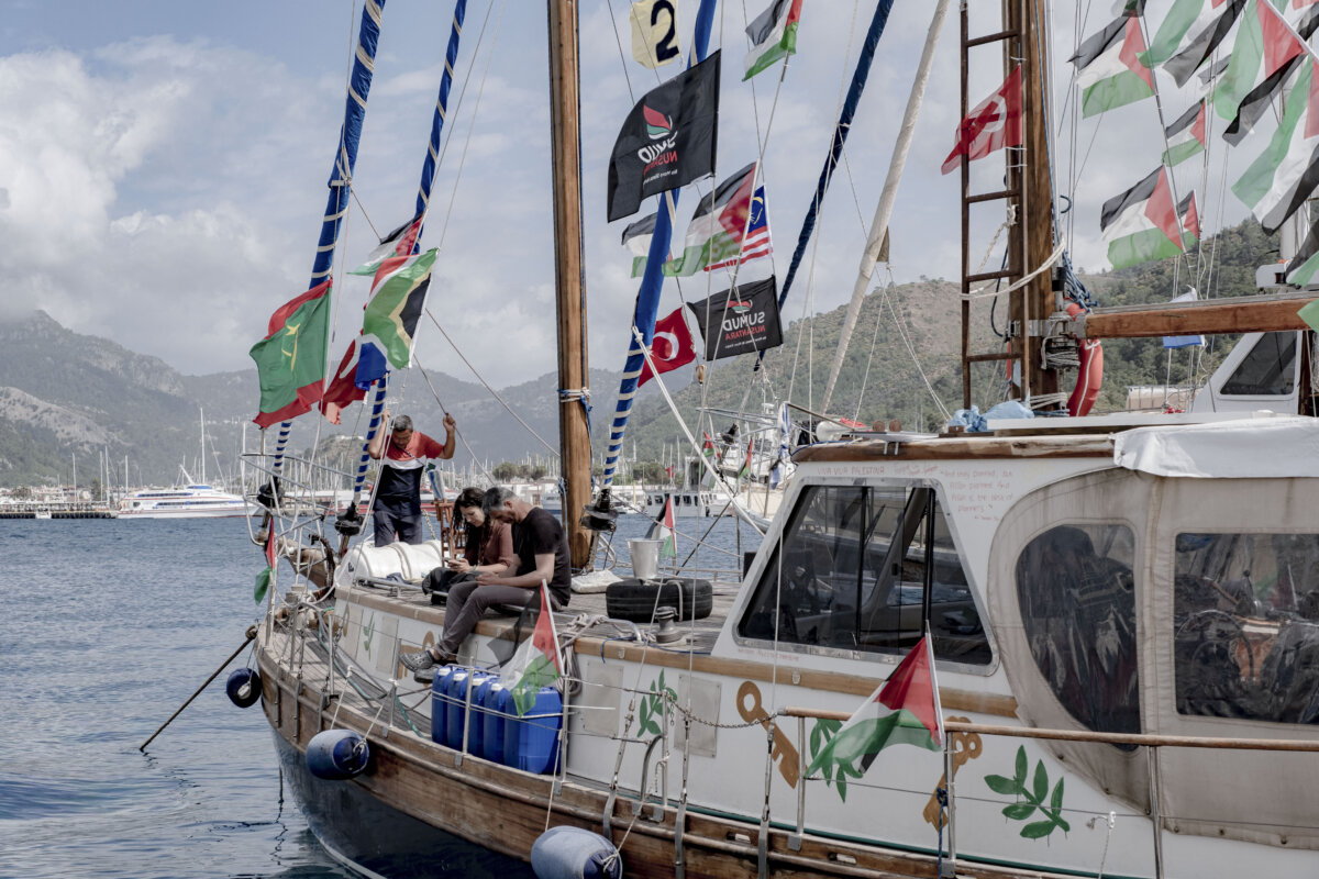 People sit on the deck of a wooden boat flying international and Palestinian flags at the port in Marmaris, Turkey, on May 14, 2026. (Murat Kocabas/Middle East Images/AFP via Getty Images)