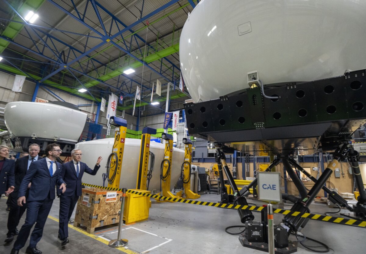 CAE Inc. chief executive Matthew Bromberg (L) and Prime Minister Mark Carney tour company facilities in Montreal, on Feb. 17, 2026. (The Canadian Press/Christinne Muschi)