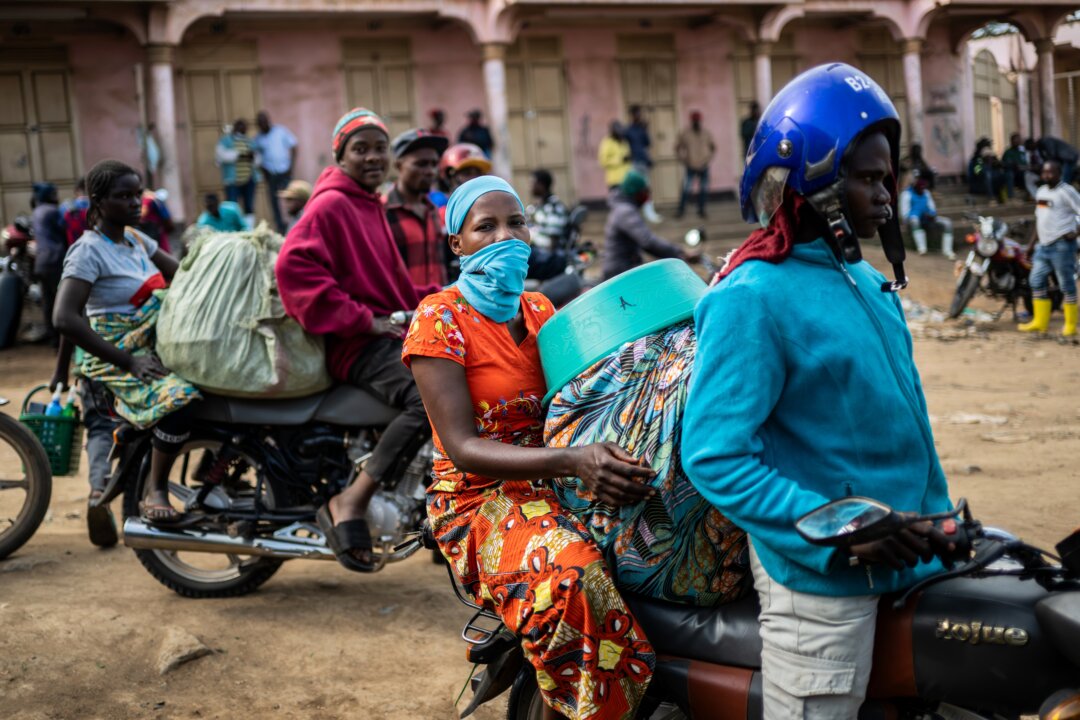 Motorcycle taxi riders and their passengers wait at the entrance to the central market while sanitation workers disinfect the area, as Ituri Province continues to combat an Ebola outbreak in Bunia, Congo, on May 23, 2026. (Moses Sawasawa/AP Photo)