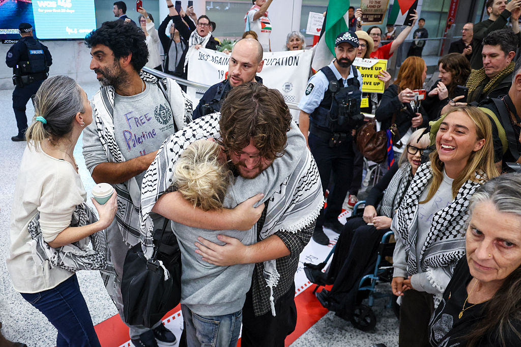Members of a Gaza-bound flotilla, that were detained by Israeli security forces last week, hug family members and friends after arriving at Sydney International Airport in Australia on May 25, 2026. (David Gray/AFP via Getty Images)