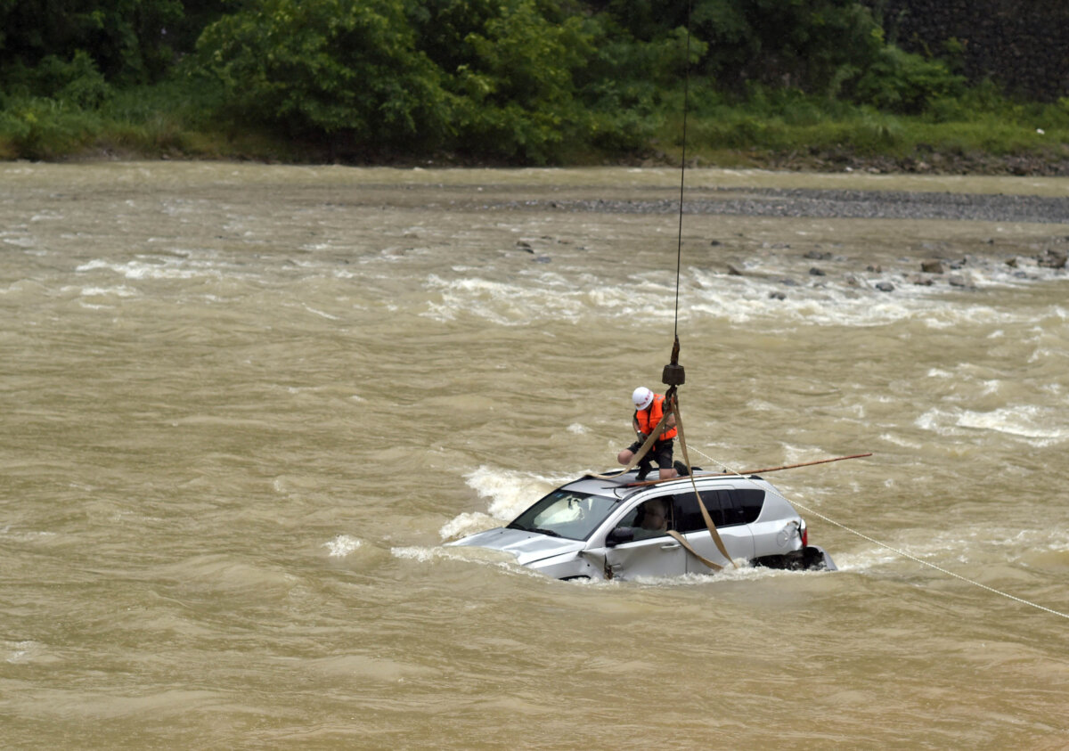 A fireman transfers a car trapped in a flood with the help of a crane at Wuxi County in Chongqing, China, on July 14, 2015. (Getty Images)