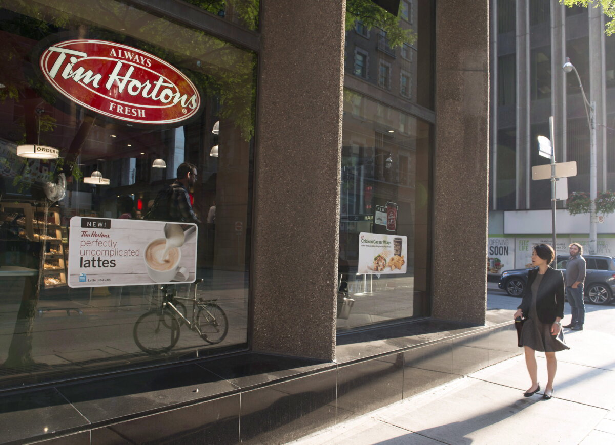 A woman walks past a Tim Hortons in Toronto in a file photo. (The Canadian Press/Doug Ives)