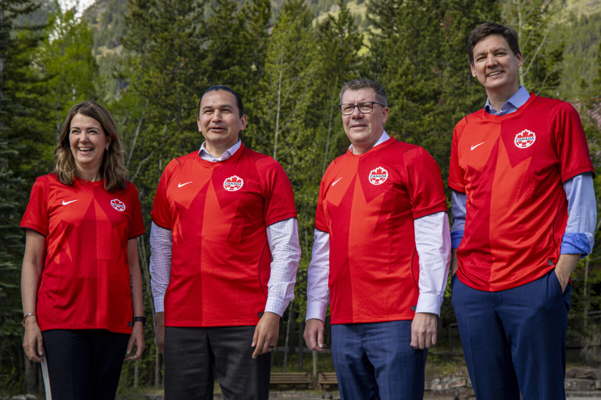 (L–R) Alberta Premier Danielle Smith, Manitoba Premier Wab Kinew, Saskatchewan Premier Scott Moe, and B.C. Premier David Eby pose wearing Team Canada soccer jerseys during a group photo at a meeting of western premiers in Kananaskis, Alta., on May 26, 2026. (The Canadian Press/Jeff McIntosh)