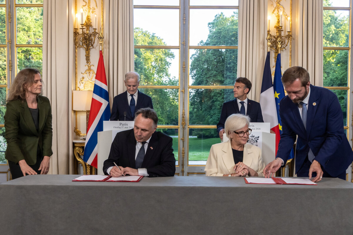 French President Emmanuel Macron (back R) and Norwegian Prime Minister Jonas Gahr Stoere (back L) stand behind Norwegian Defense Minister Tore Sandvik (seated L) and French Armed Forces and Veterans Affairs Minister Catherine Vautrin (seated R) as they sign an agreement before a working dinner at the Élysée Palace in Paris on May 27, 2026. (Christophe Petit Tesson/Reuters)