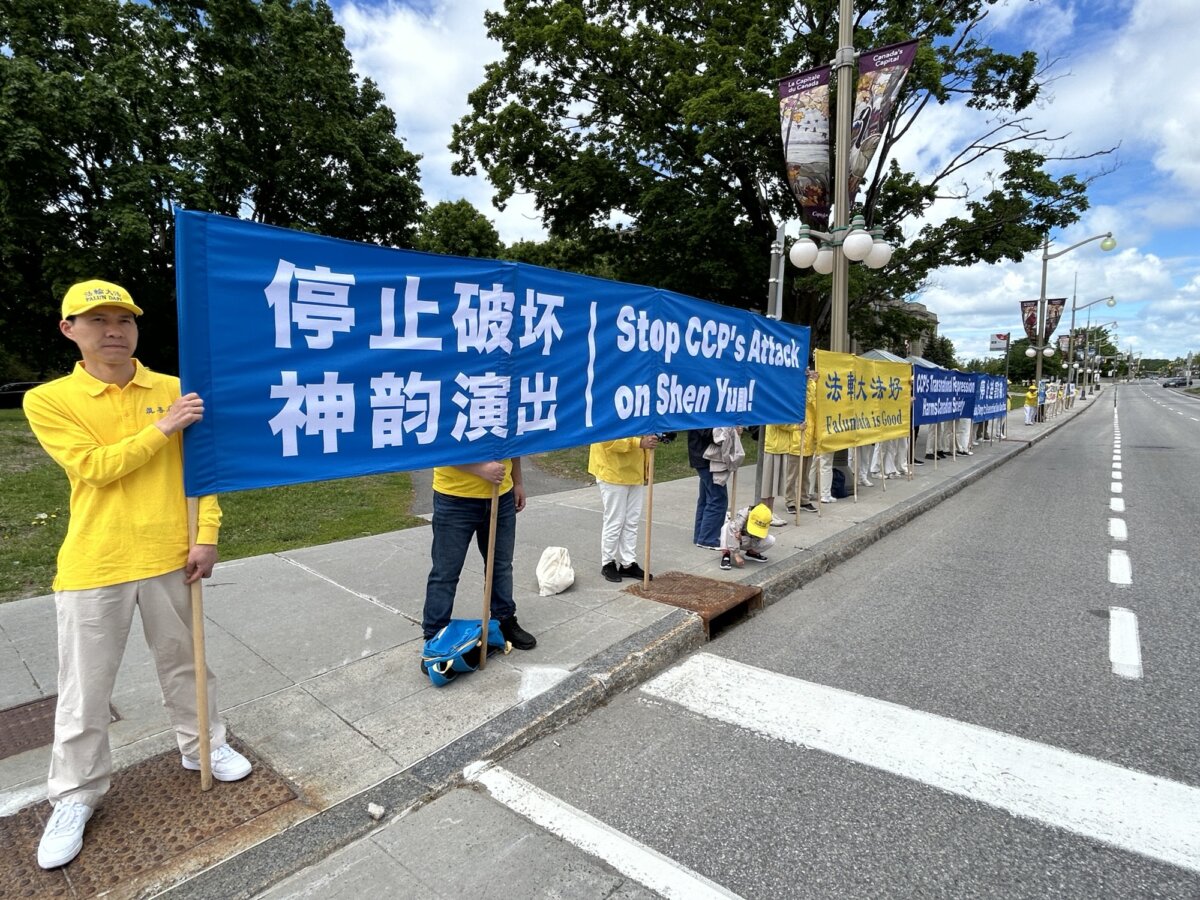 Falun Gong practitioners hold banners in front of the Global Affairs building in Ottawa in protest of the visit by Chinese Foreign Affairs Minister Wang Yi to Canada, on May 28, 2026. (The Epoch Times)