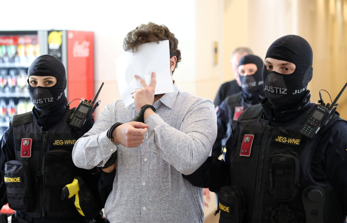 Beran A is escorted by security personnel during a break in a courtroom for his trial in Wiener Neustadt, Austria, on April 28, 2026. (Leonhard Foeger/Reuters)