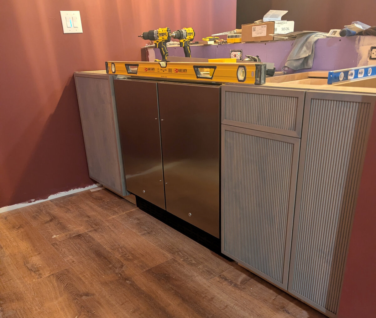 There are three cabinets in this photo. A sink base is to the left of the refrigerator/freezer. A trash-can cabinet and small slide-out shelf cabinet are to the right. This is the bar area of a basement speakeasy. (Tim Carter/Tribune Content Agency/TNS)