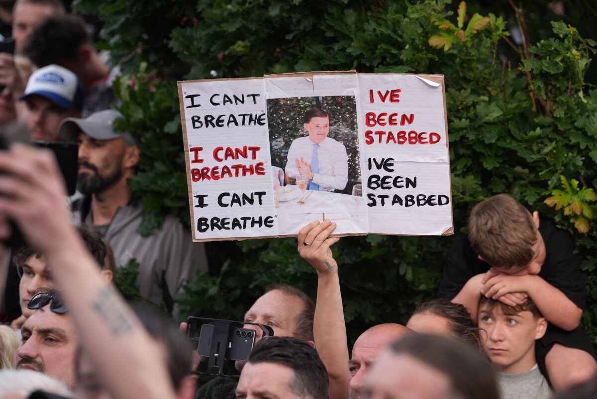 A protester holds up a sign with a photograph of murdered Henry Nowak during a protest outside a police station in Southampton, England, on June 2, 2026. (Gareth Fuller/PA via AP)