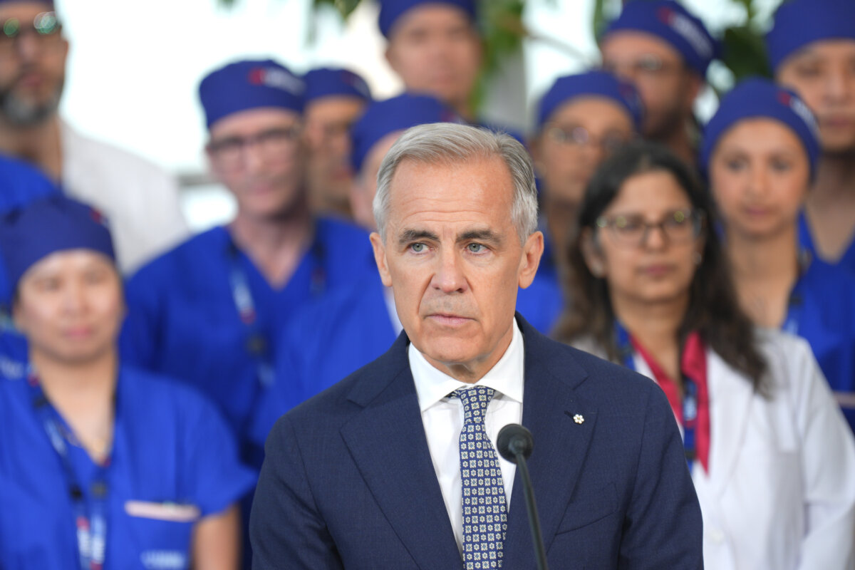 Prime Minister Mark Carney stands in front of medical staff as he delivers remarks at Toronto General Hospital in Toronto, on June 4, 2026. (The Canadian Press/Chris Young)