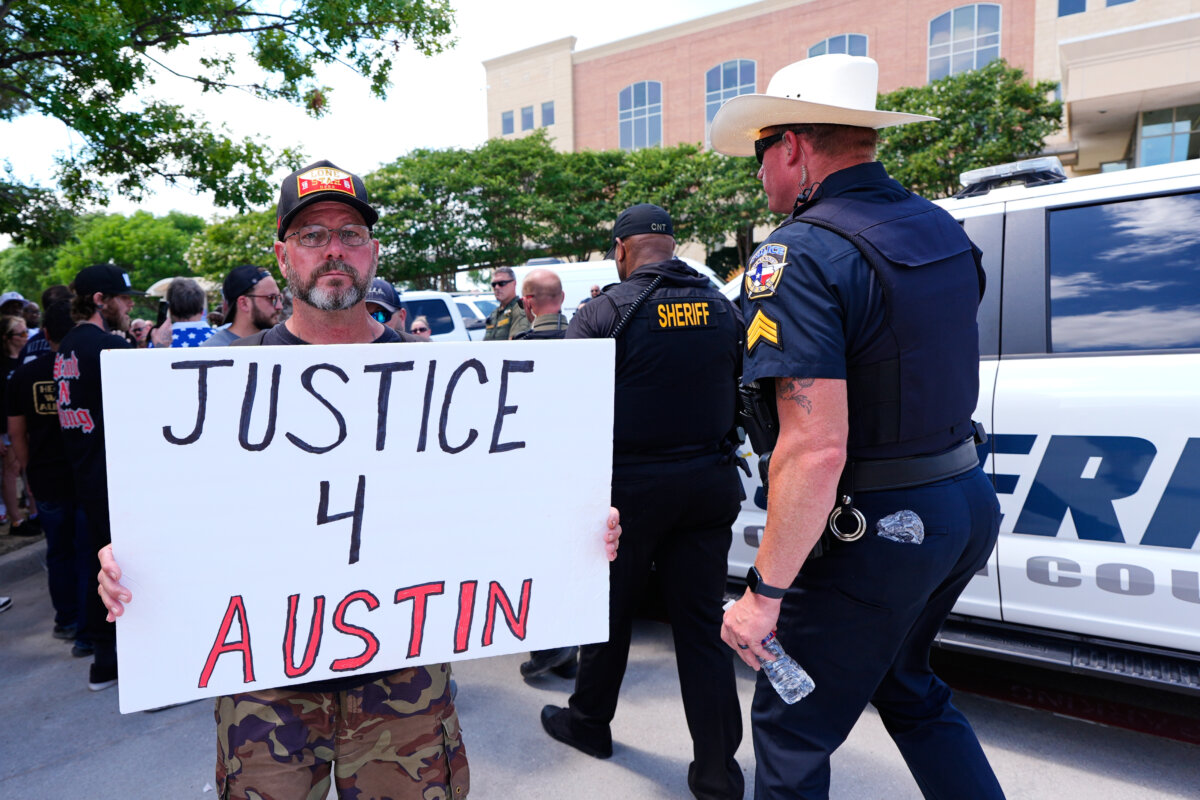 An Austin Metcalf supporter holds a sign as law enforcement officials walk past in front of the Collin County Courthouse following the verdict in the trial reached in McKinney, Texas, on June 9, 2026. (Tony Gutierrez/AP Photo)