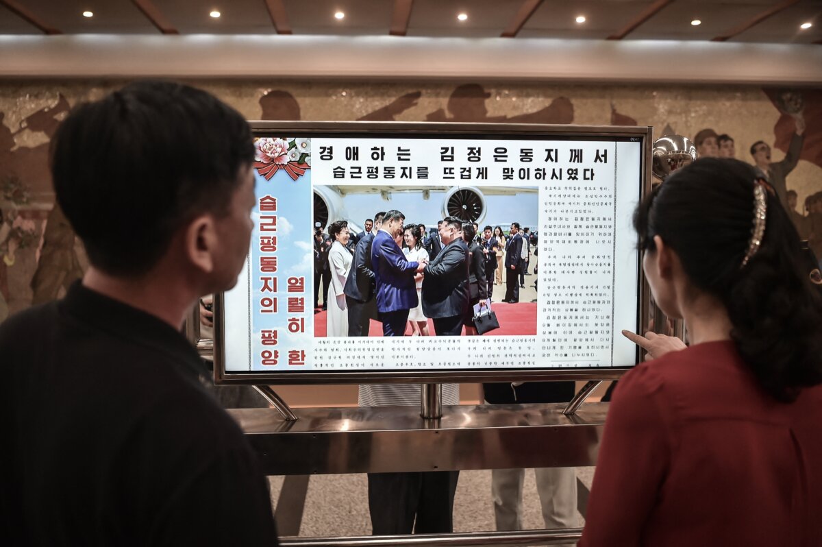 People look at a screen with the newspaper "Rodongsinmun" showing the news on the visit of China's President Xi Jinping, in the Kaeson Station of the Pyongyang Metro in Pyongyang on June 9, 2026. (Kim Won Jin / AFP via Getty Images)