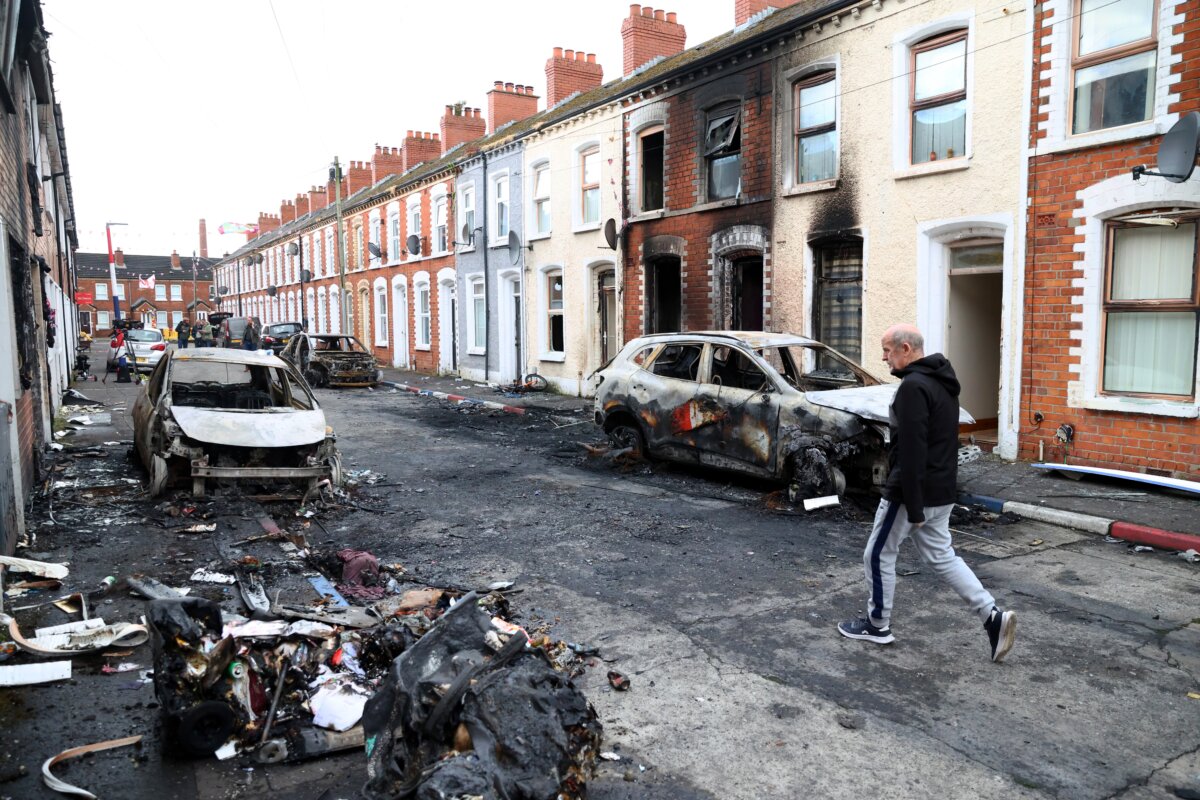 A man walks down a street where rioting erupted over a stabbing that left the victim seriously injured, in east Belfast, Northern Ireland, on June 10, 2026. (AP Photo/Peter Morrison)