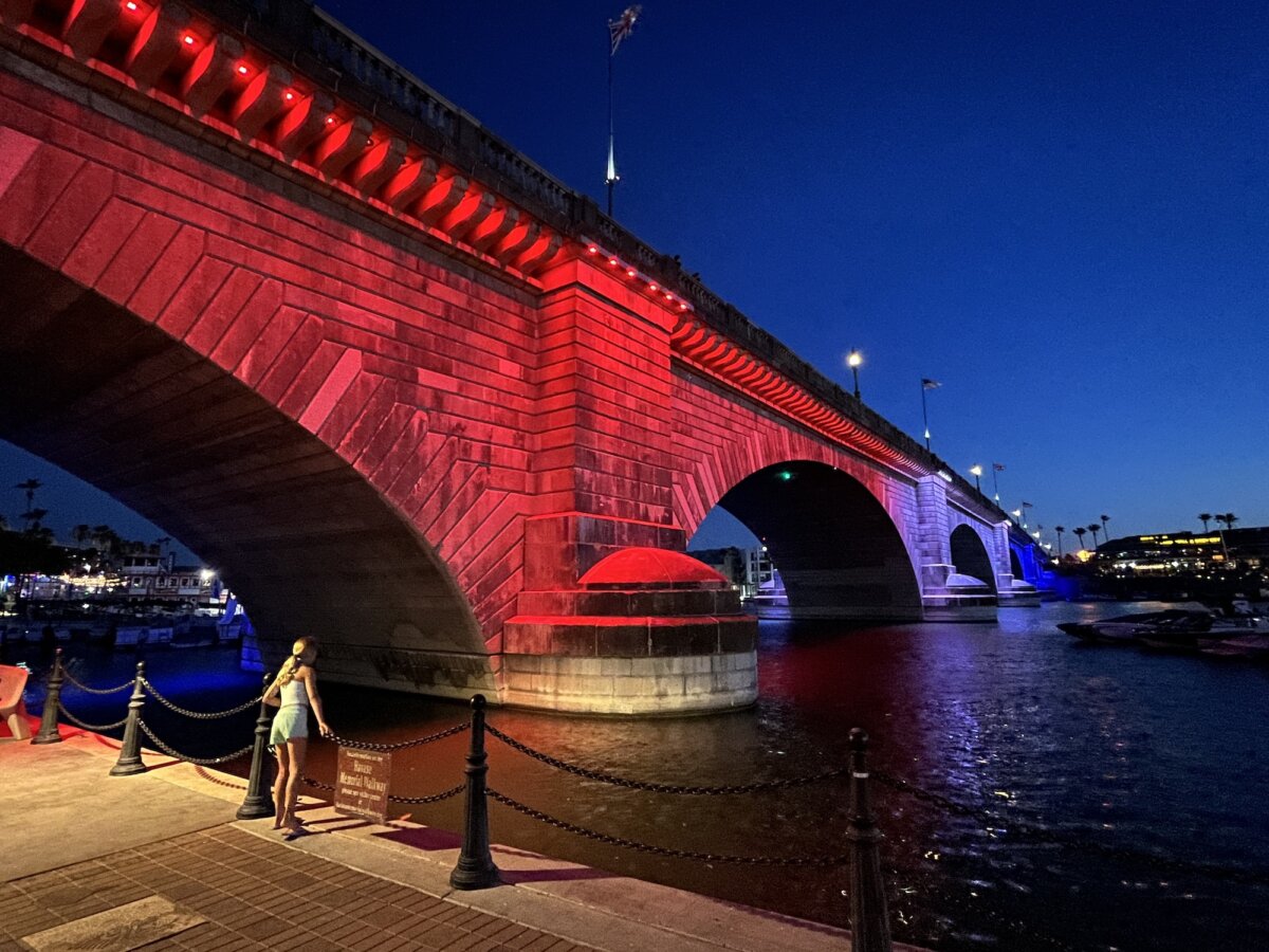 A woman marvels at the red light illuminating the 1831 London Bridge in Lake Havasu City, Ariz., on June 5, 2026. (Allan Stein/The Epoch Times)
