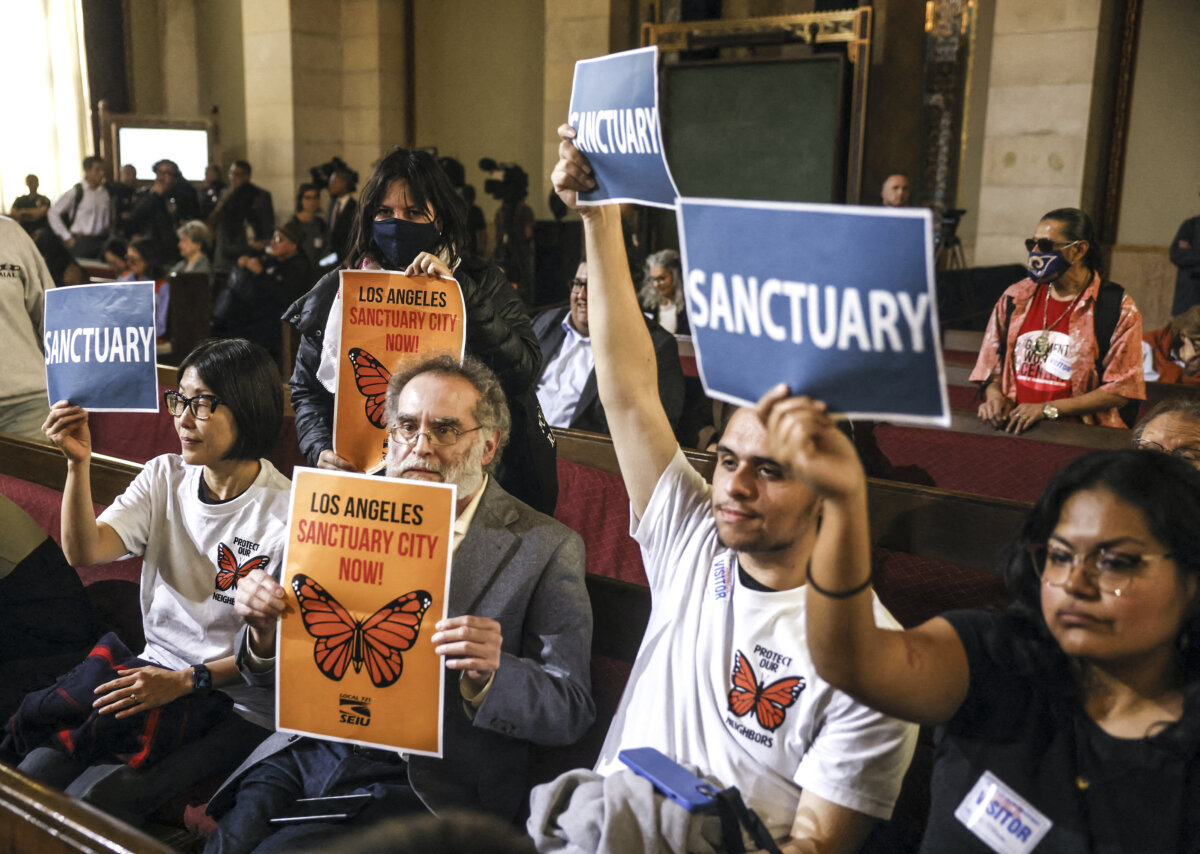 People in the audience hold up signs as the Los Angeles City Council considers a "sanctuary city" ordinance during a meeting at City Hall in Los Angeles on Nov. 19, 2024. (Etienne Laurent/AFP via Getty Images)