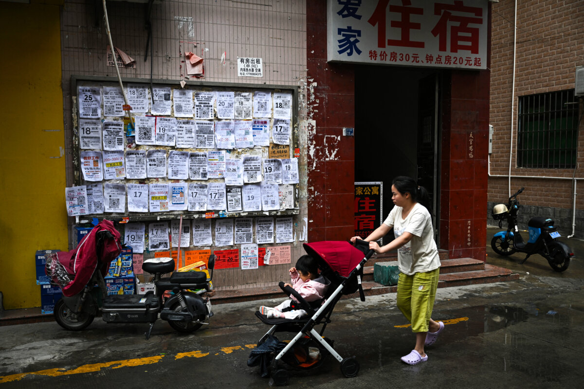 A woman pushes a stroller with a baby next to job advertisements displayed on a board in Foshan, Guangdong province, in China, on April 28, 2026. (Pedro Pardo / AFP via Getty Images)