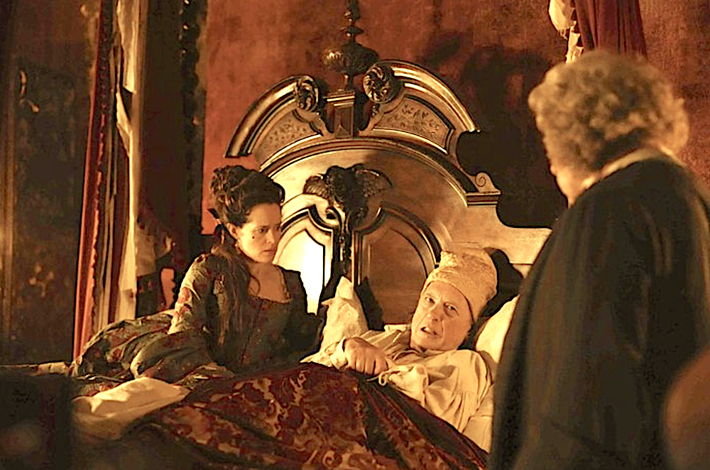 woman tends to bed-ridden man as doctor looks on in Savage House