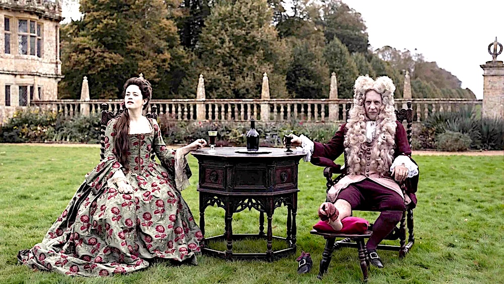 man and woman in period dress sitting on a lawn in Savage House