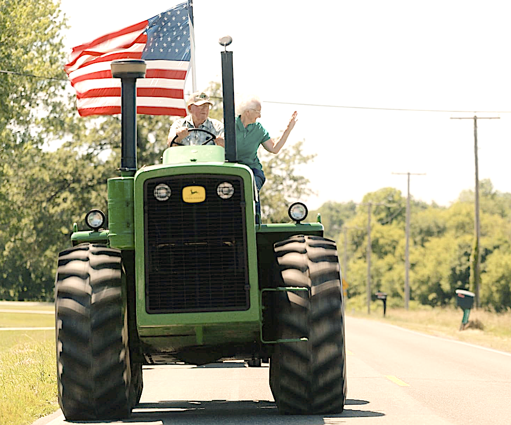 Big, green John Deere tractor on the road in Flag Day