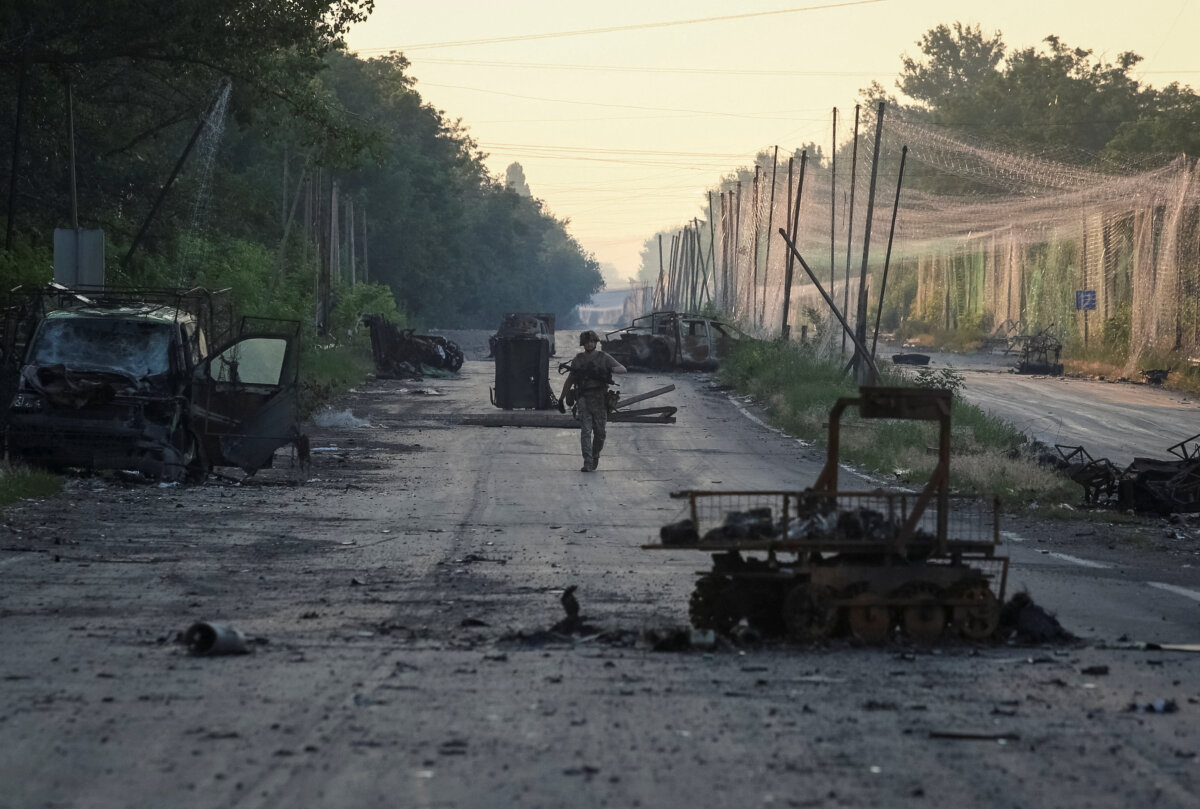 A serviceman of the consolidated Brigade 'Khyzhak' of the Ukrainian Patrol Police Department walks along a road near anti-drone nets and destroyed military vehicles as he takes part in a mission to protect a road from Russian drones between frontline towns of Druzhkivka and Kostiantynivka, in the Donetsk region of Ukraine, on June 24, 2026. (Anatolii Stepanov/Reuters)