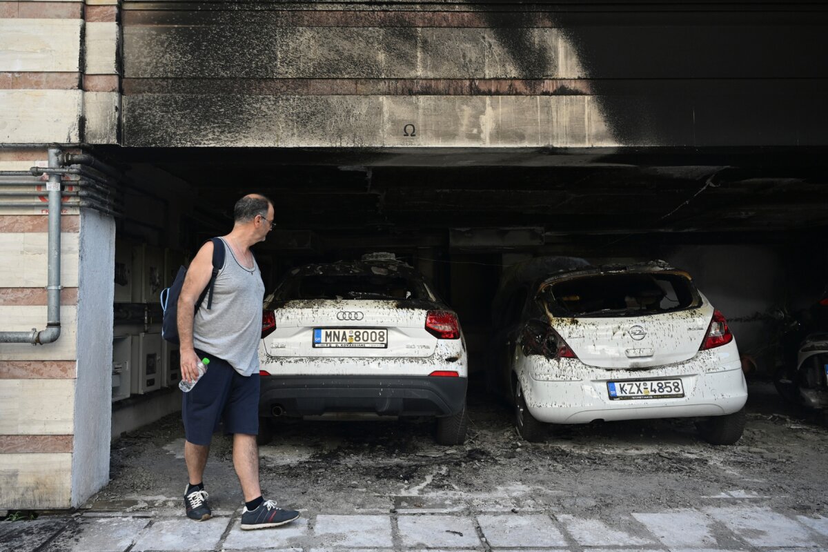 A man looks at burned vehicles following firebomb attacks that apparently targeted members of Greece's governing conservative New Democracy party in the northern port city of Thessaloniki, Greece, on July 1, 2026. (Giannis Papanikos/AP)
