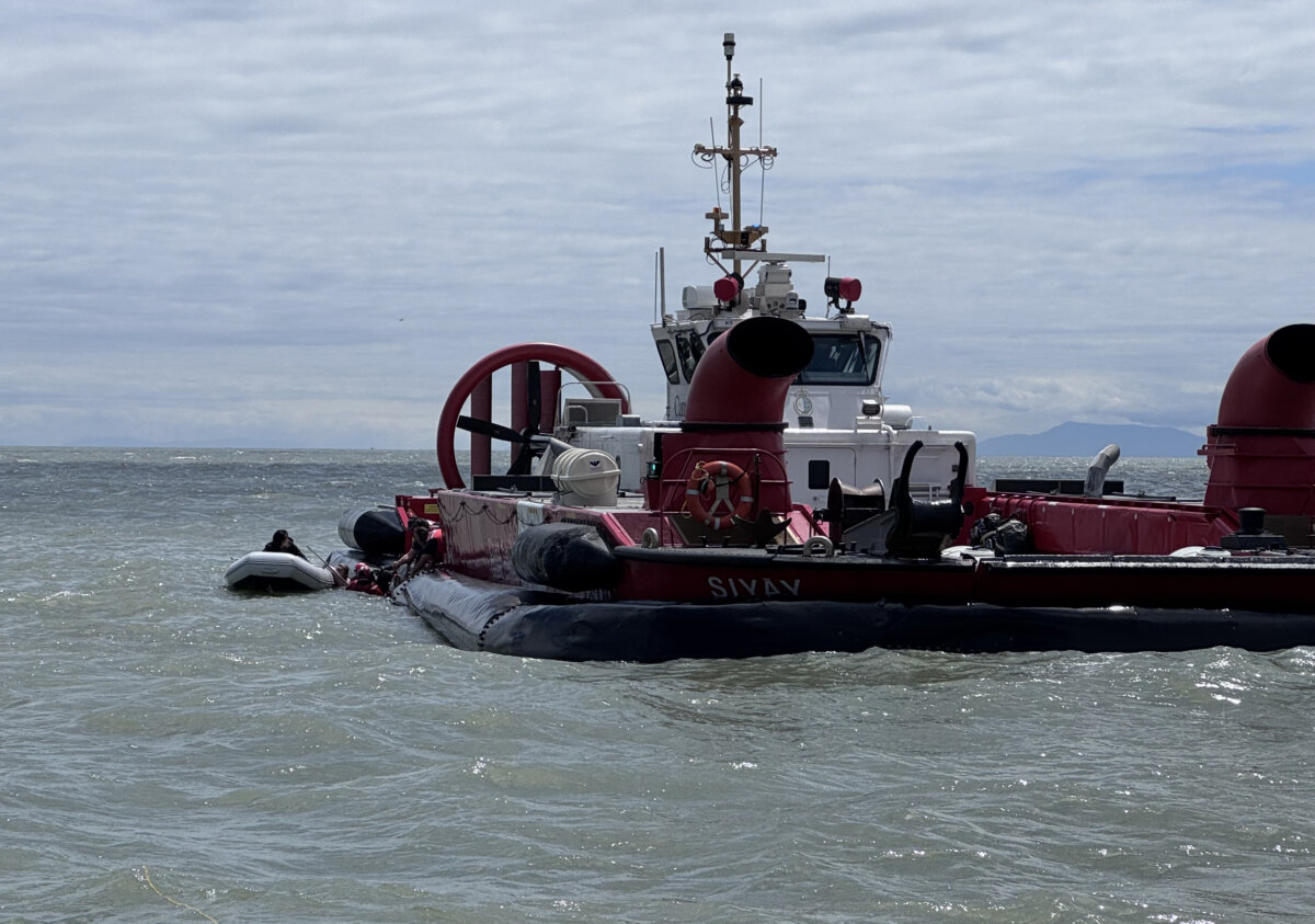 Survivors of the sinking of a fishing charter boat in the Strait of Georgia are seen in an inflatable dinghy being helped by Coast Guard officers on June 28, 2026, in this photo taken by sailor Dorothy Stauffer, who helped rescue them. (The Canadian Press/Handout-Dorothy Stauffer)
