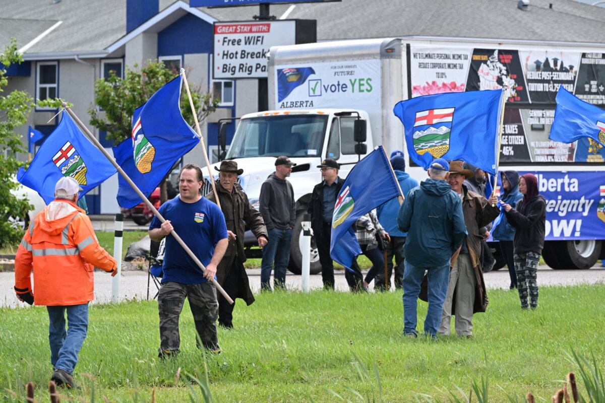 Demonstrators carrying Alberta flags gather near a truck displaying pro-Alberta sovereignty messages during a rally in Taber, Alta., on June 28, 2026. (The Canadian Press/Matthew Bruce)
