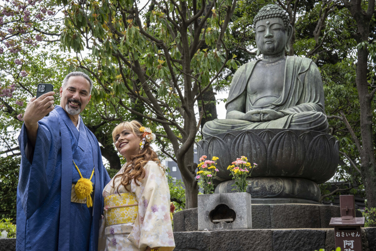 Foreign tourists take selfies with a statue of Buddha in the Asakusa area of Tokyo on April 15, 2026. A record number of tourists visited Japan in March, the official tourism board said on April 15, despite a sharp drop in Chinese visitors after the relationship between Beijing and Tokyo have soured. (Yuichi Yamazaki/AFP/Getty Images/TNS)
