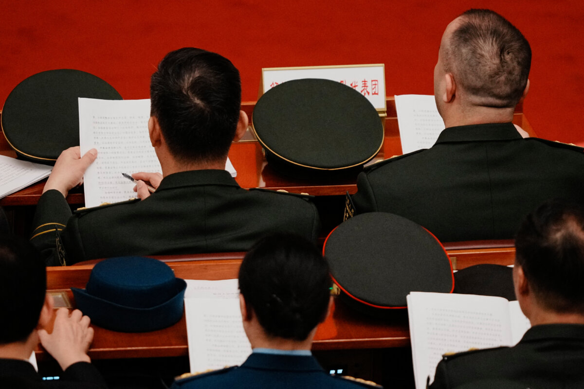 Delegates read documents during a plenary session of China's rubber-stamp National People's Congress in Beijing on March 9, 2026. (Vincent Thian/Pool/AFP via Getty Images)