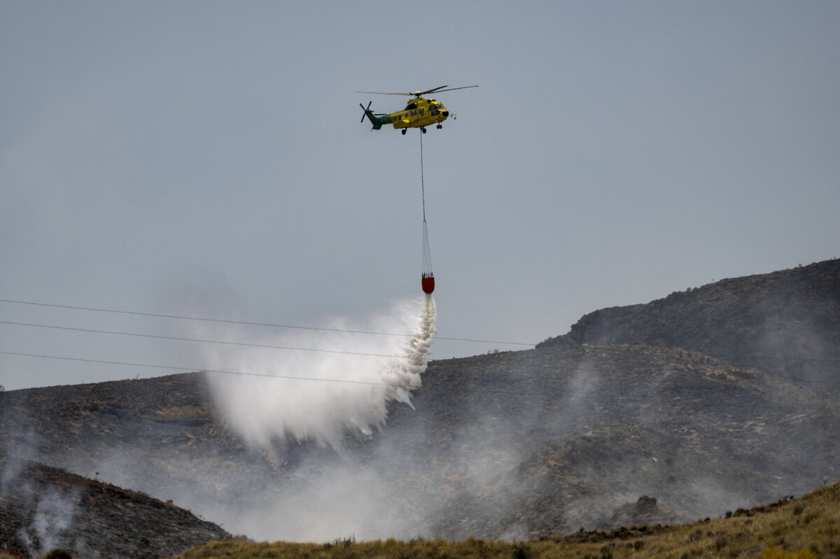 A helicopter drops water over the area of one of Spain’s deadliest wildfires, which killed at least 12 people and burned about 16,300 acres in Almeria Province, Spain, on July 11, 2026. (Jorge Guerrero/AFP via Getty Images)