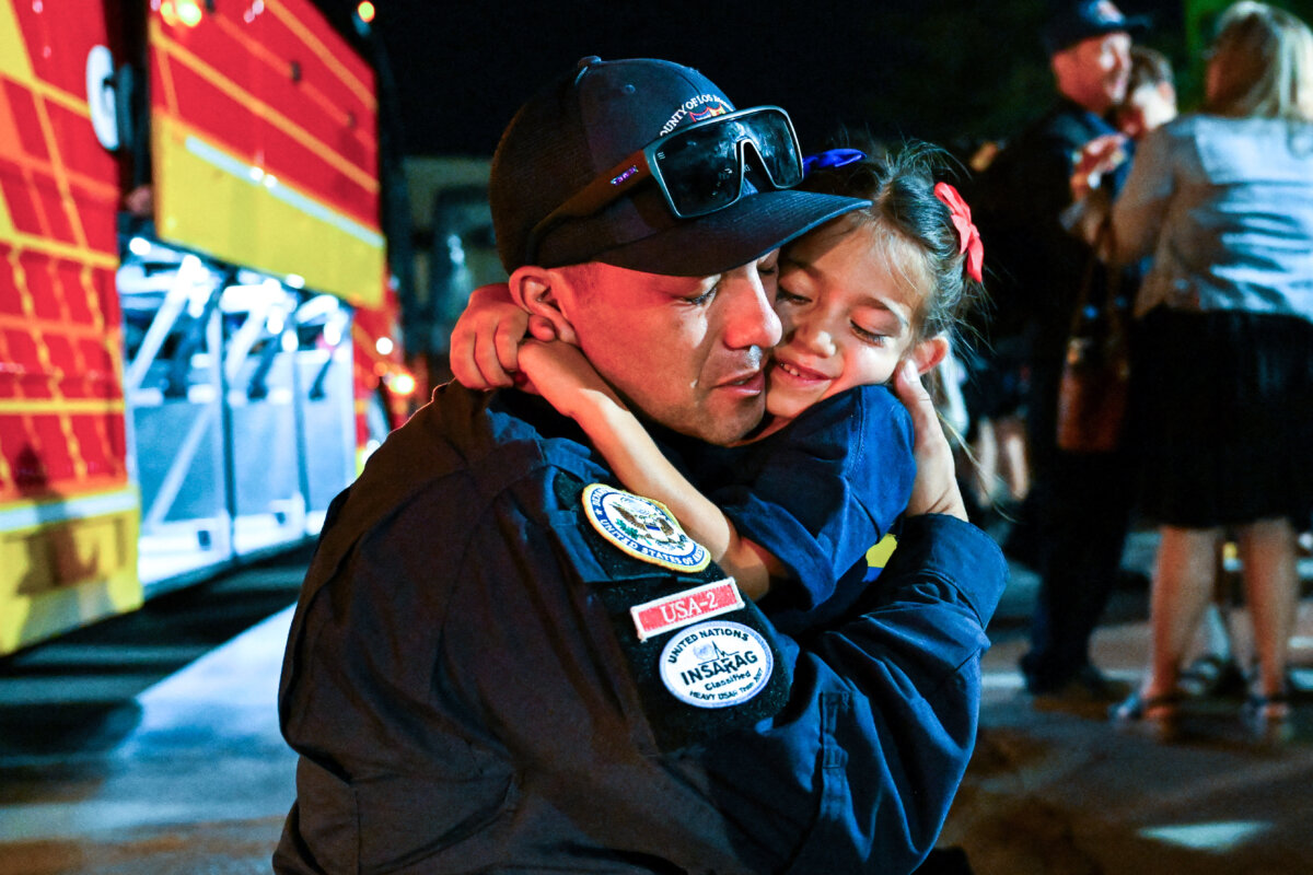 A member of the Los Angeles County Fire Department USA-2 international urban search and rescue team is reunited with his family after returning from rescue efforts following the earthquakes in Venezuela at the LACoFD Technical Operations Section in Los Angeles on July 6, 2026. (Patrick T. Fallon/AFP via Getty Images)
