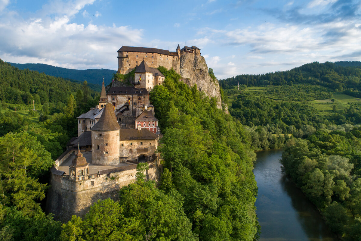 The Orava Castle in Slovakia is built from stone quarried right from the surrounding landscape. Thick masonry walls blend into the rock face itself, while three fortified gates and narrow walled passages lead to a sturdy Southern Bastion, a reinforced stronghold built to guard the castle's most vulnerable approach. Forested hills and rugged Carpathian peaks frame the scene in every direction. (Nahlik/Shutterstock)
