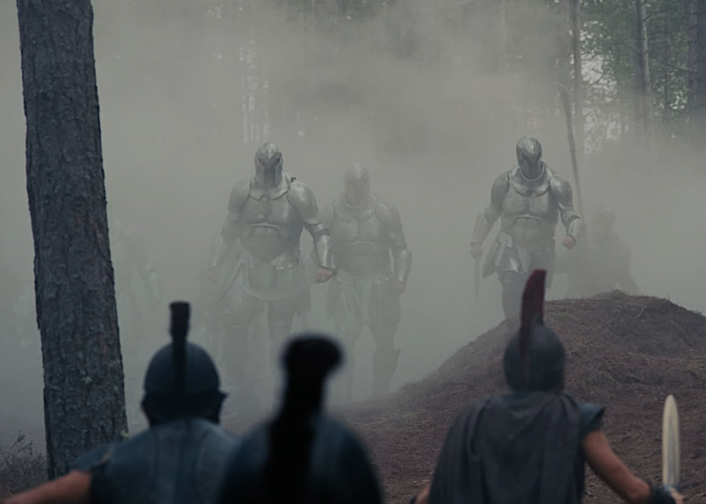 giant armor-wearing creatures advance through a wooded area in The Odyssey