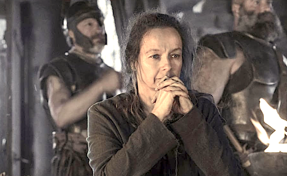 women sits at table with warriors standing behind her in The Odyssey