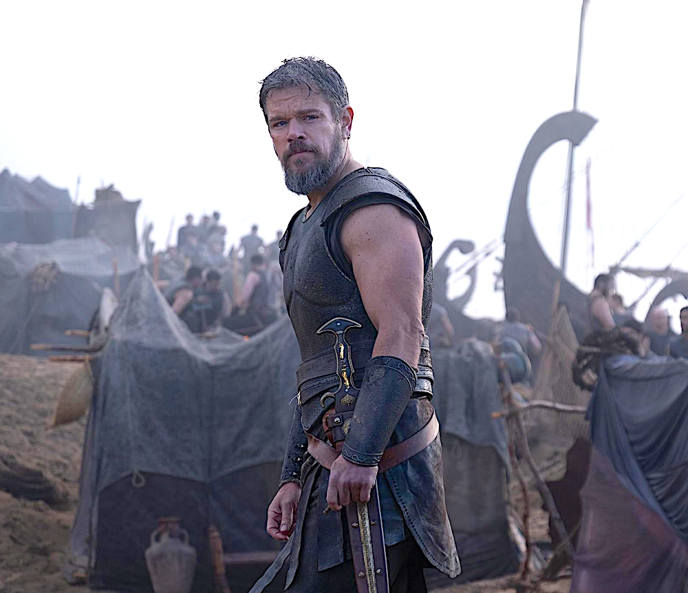 man stands with warriors in front of ships in The Odyssey